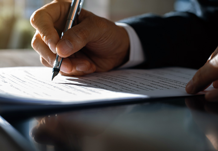 Um homem a assinar um contrato com uma caneta