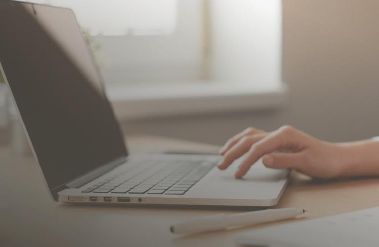 Grande plano das mãos de uma pessoa a escrever num computador portátil